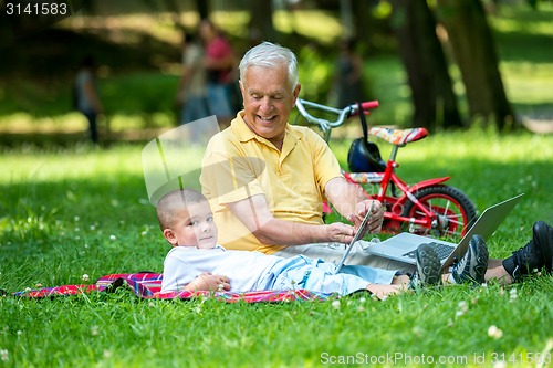 Image of grandfather and child in park using tablet