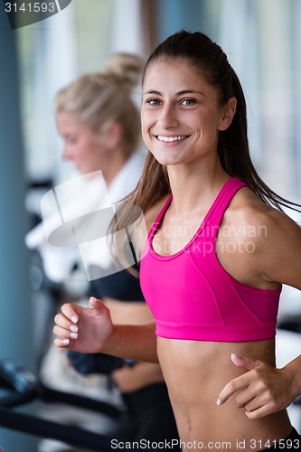 Image of friends  exercising on a treadmill at the bright modern gym