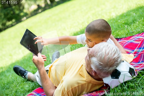 Image of grandfather and child in park using tablet