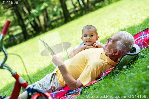 Image of grandfather and child in park using tablet