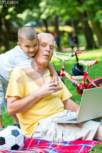 Image of grandfather and child using laptop