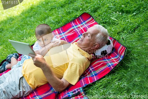 Image of grandfather and child in park using tablet