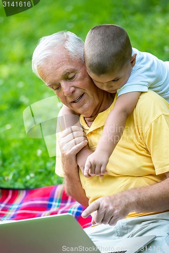 Image of grandfather and child using laptop