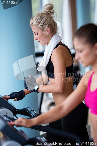 Image of friends  exercising on a treadmill at the bright modern gym