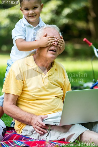 Image of grandfather and child using laptop