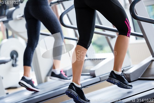 Image of friends  exercising on a treadmill at the bright modern gym
