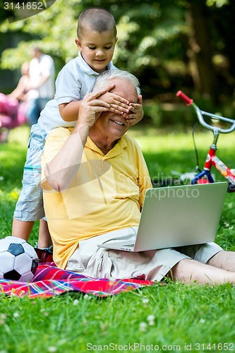 Image of grandfather and child using laptop