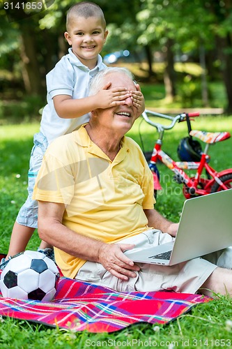 Image of grandfather and child using laptop