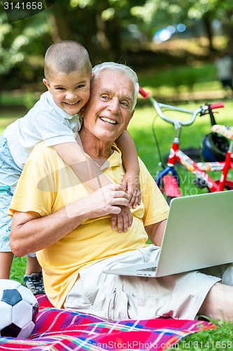 Image of grandfather and child using laptop