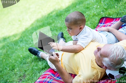 Image of grandfather and child in park using tablet