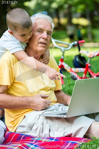 Image of grandfather and child using laptop