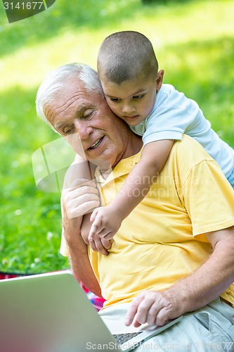 Image of grandfather and child using laptop