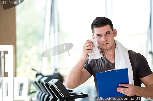 Image of trainer with clipboard standing in a bright gym