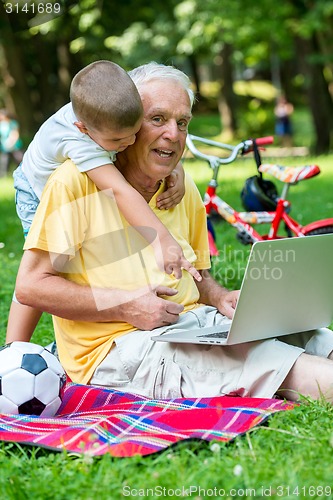 Image of grandfather and child using laptop