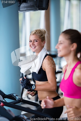 Image of friends  exercising on a treadmill at the bright modern gym