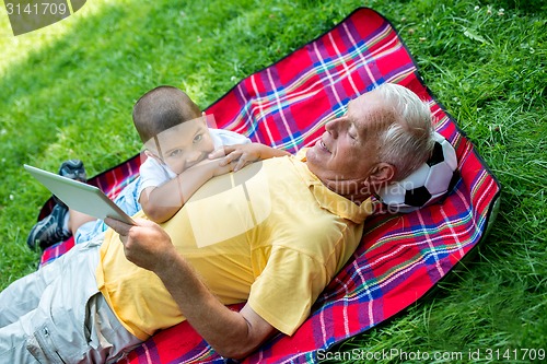 Image of grandfather and child in park using tablet