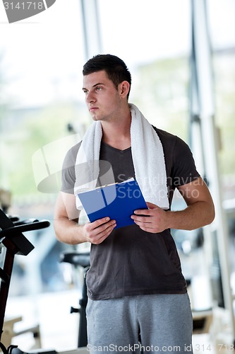 Image of trainer with clipboard standing in a bright gym