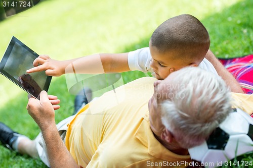 Image of grandfather and child in park using tablet