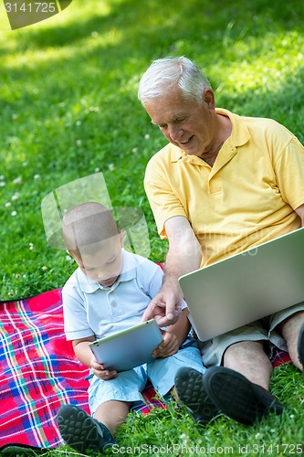 Image of grandfather and child in park using tablet