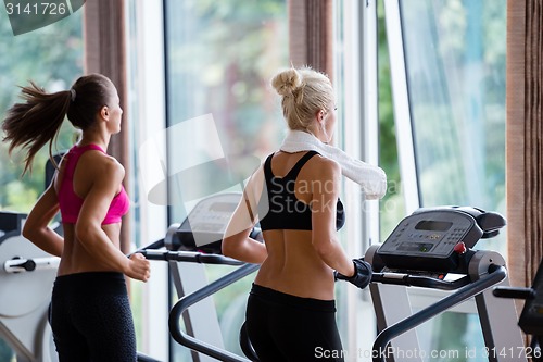 Image of friends  exercising on a treadmill at the bright modern gym