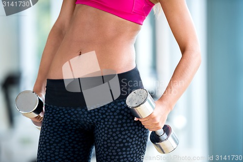 Image of lifting some weights and working on her biceps in a gym