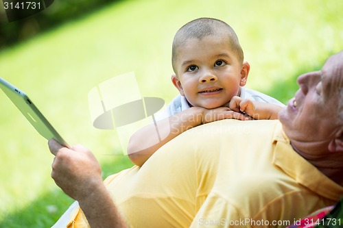 Image of grandfather and child in park using tablet