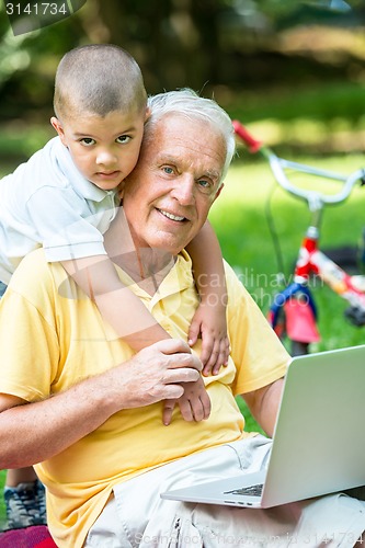 Image of grandfather and child using laptop