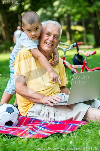 Image of grandfather and child using laptop