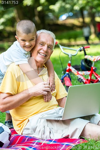 Image of grandfather and child using laptop