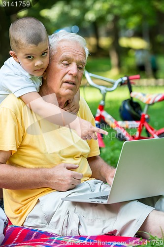 Image of grandfather and child using laptop