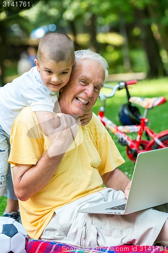 Image of grandfather and child using laptop