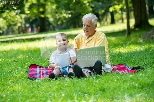 Image of grandfather and child in park using tablet