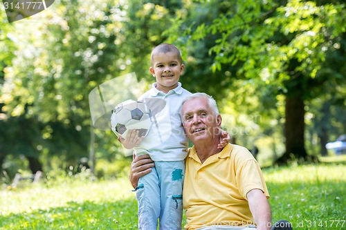 Image of grandfather and child in park using tablet