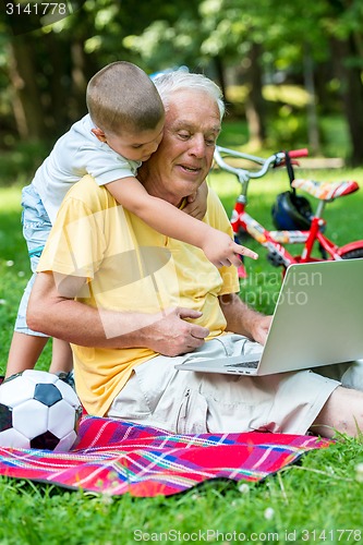 Image of grandfather and child using laptop