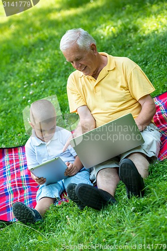 Image of grandfather and child in park using tablet