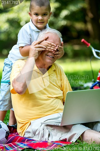 Image of grandfather and child using laptop