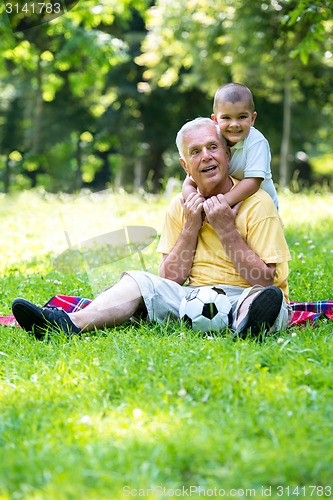 Image of grandfather and child in park using tablet