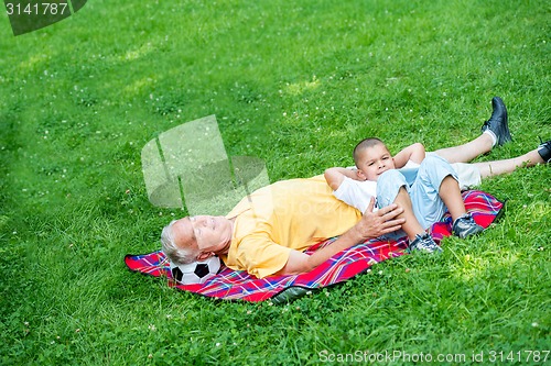 Image of grandfather and child in park using tablet