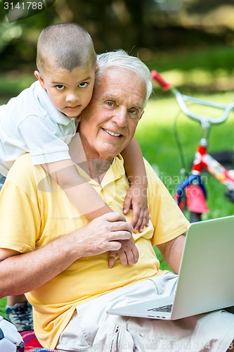 Image of grandfather and child using laptop