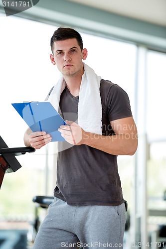 Image of trainer with clipboard standing in a bright gym