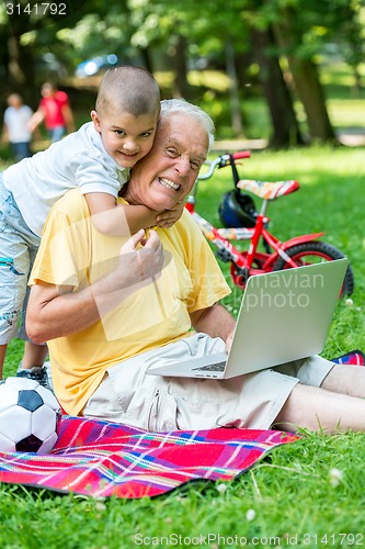 Image of grandfather and child using laptop