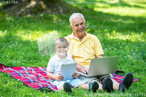 Image of grandfather and child in park using tablet
