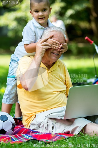 Image of grandfather and child using laptop