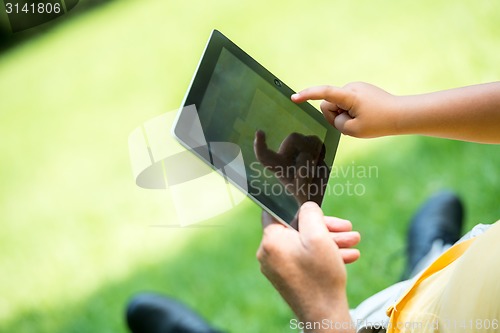 Image of grandfather and child in park using tablet