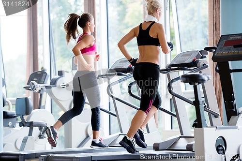 Image of friends  exercising on a treadmill at the bright modern gym