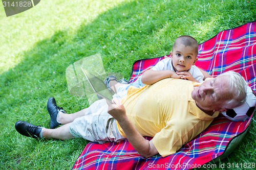 Image of grandfather and child in park using tablet
