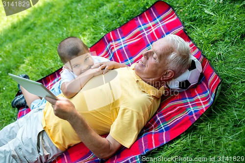 Image of grandfather and child in park using tablet