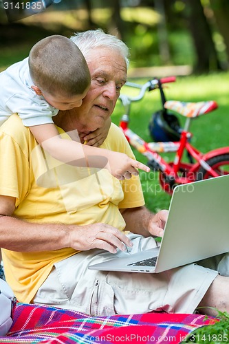 Image of grandfather and child using laptop