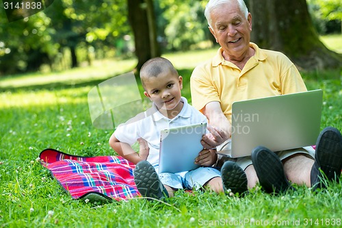 Image of grandfather and child using laptop