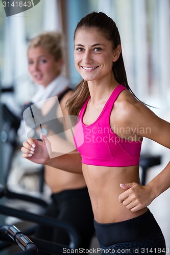 Image of friends  exercising on a treadmill at the bright modern gym